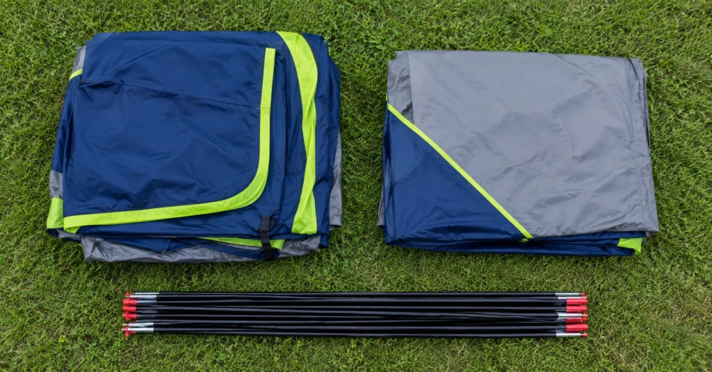 Coleman Sundome 4-person tent body, rainfly, and poles laid out on grass
