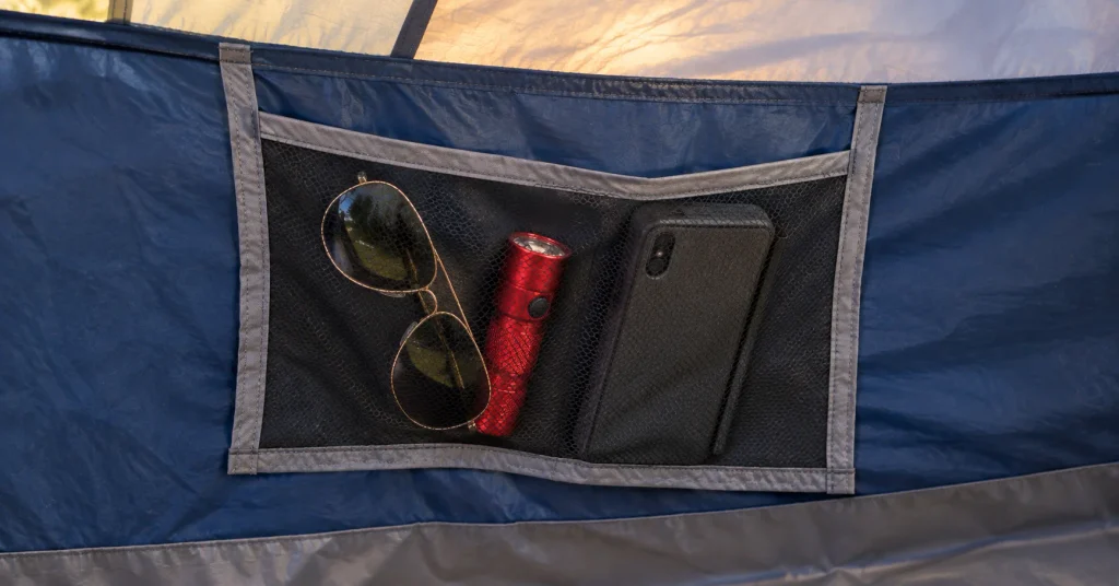 Interior gear pocket of the Coleman Sundome tent holding sunglasses and a flashlight